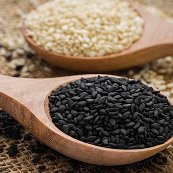 Black sesame and white sesame seed on wooden spoon